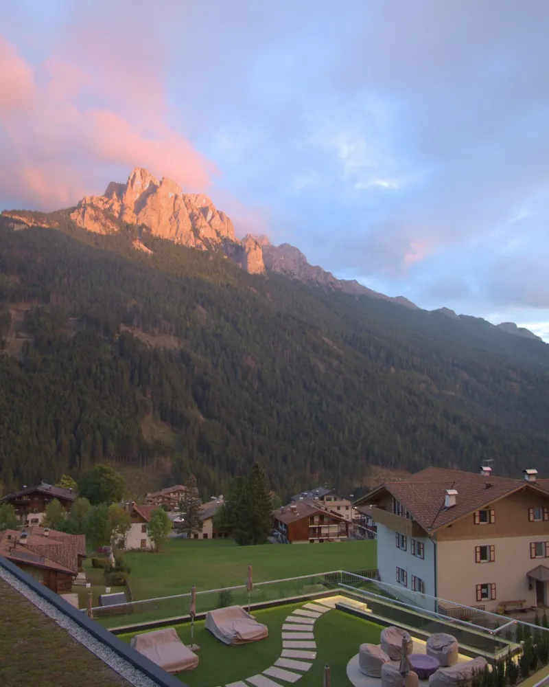 Cima rocciosa accesa di rosa al tramonto sopra un paese di montagna